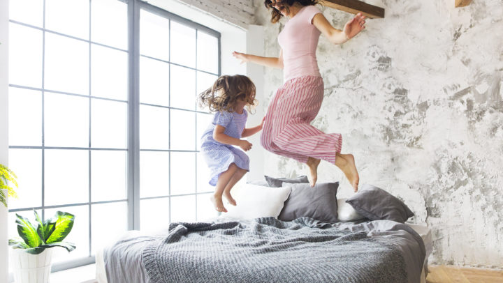 Family fun. Mother and daughter jumping on the bed