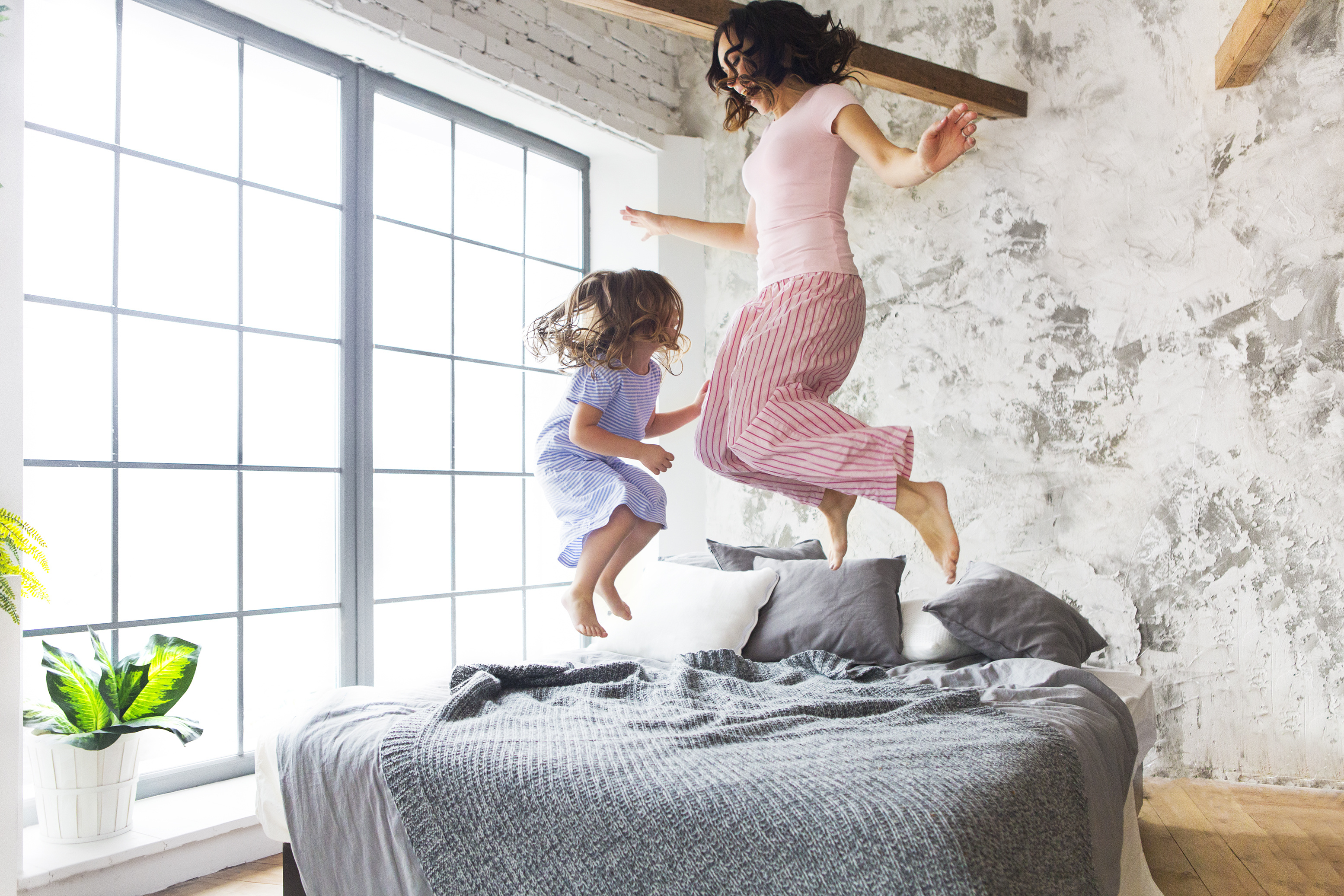 Family fun. Mother and daughter jumping on the bed